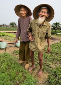 Vietnamese Farmer Couple Hand in Hand in the Garden. Their expression shows authentic communication.